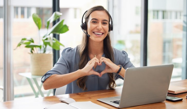 Confident and happy female entrepreneur showing love and positivity while working with headphones.