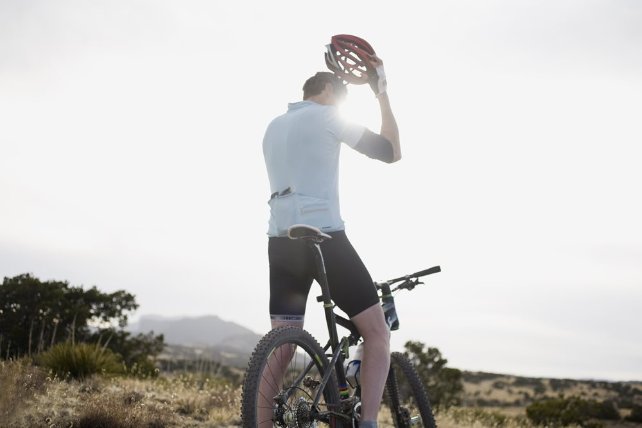 Sportive man on a bike taking off his helmet
